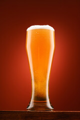 glass of beer, on wooden stand, with red background, object close-up, beer bubbles and foam
