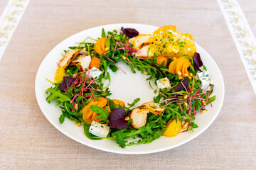 Colorful salad with greens, mango, and cheese on a beautiful plate
