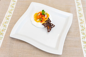 Colorful fruit dessert served on white plate with chocolate decoration