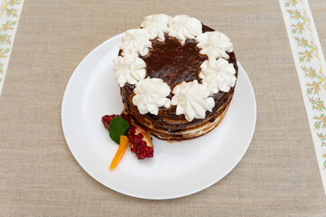 Chocolate layered cake with cream and fresh fruit garnishment on a plate
