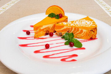 Delicious orange dessert served on a white plate with berry sauce