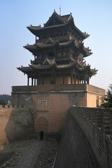A traditional Chinese tower house stands majestically along the river, with the main entryway passing directly through the base of the tower.