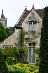 Fototapeta premium View of a stone house and church in the picturesque village of Castle Combe, Cotswolds, Wiltshire England, UK