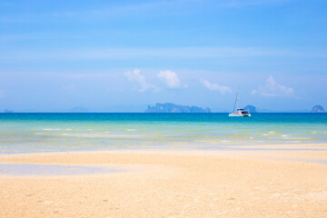 Seascape. Sandy beach with boat in azure sea water and islands in the sea on the horizon in Krabi province Thailand