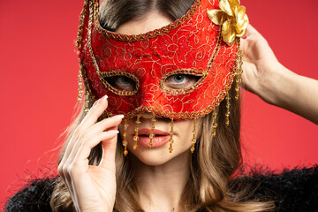 Fashion model wearing red venetian mask posing on red background