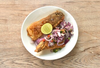 fried dry pickled fish taste sour and salty topping chop shallot and chili with slice lemon salad on plate 