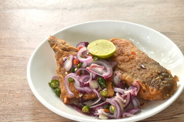 fried dry pickled fish taste sour and salty topping chop shallot and chili with slice lemon salad on plate 