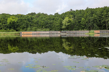 An einem See befindet sich ein Komplex mit mehreren Bootshäuser.