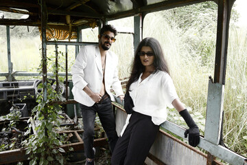 a male and female model posing in a white shirt and black trousers inside an abandoned broken down bus