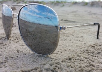 sunglasses on sand with beach reflection