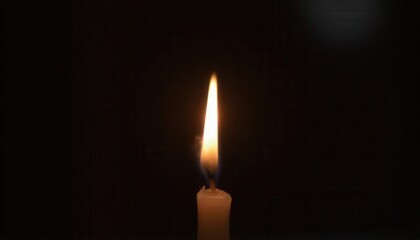 Single candle flickering in darkness representing hope and remembrance for cancer.