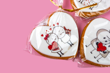 Gingerbread cookies for Valentine's Day in festive packaging on a pink background, sweet gift for Valentine's Day, cookies with cream and icing