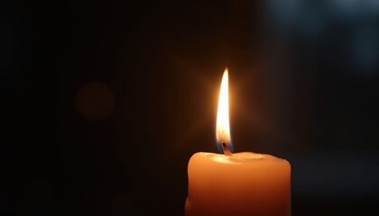 Candle glowing softly in darkness tribute to cancer patients.