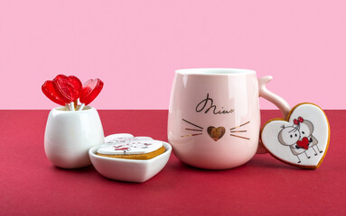 red heart-shaped lollipops in a white vase for Valentine's Day on a red and pink background, pink cup with a heart, festive still life, sweet gift for Valentine's Day