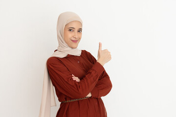 Confident woman in stylish dress and hijab giving a positive thumbs-up gesture while smiling....