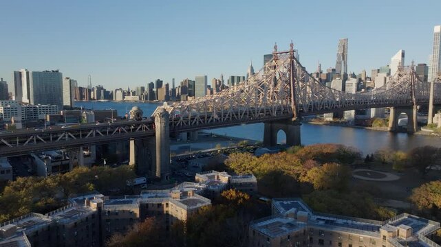 Aerial view from Queensbridge Houses of Roosevelt Island bridge linking colorful fall landscape with East River, Manhattan skyline gleaming under golden sunlight