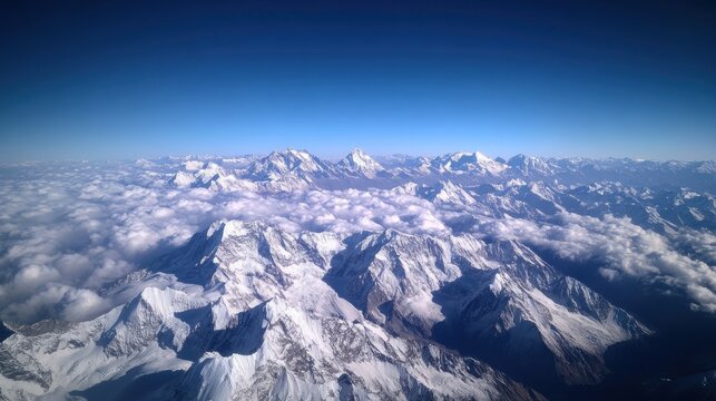 Majestic snow-capped mountain range peaks piercing through a sea of fluffy clouds under clear blue sky - Powered by Adobe