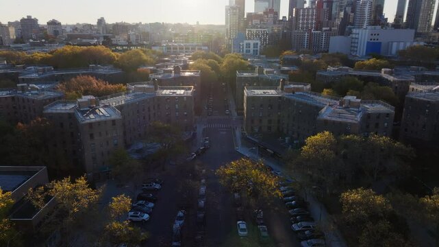 Aerial panorama capturing Queensbridge Houses, in Long Island City, Queens, New York, suburban area during sunset with parked vehicles, sparse greenery, tranquil urban setting