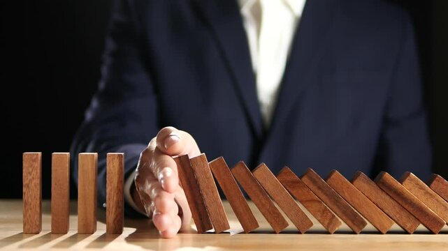 Concept of Risk Assessment, Crisis, Economic, Business Management, Inflation. Hand of businessman stopping, prevent falling block, domino effect to safe family life, property, insurance from crisis.