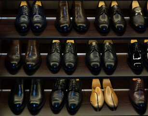 Formal black leather shoes arranged neatly on wooden shelves, classic design focus