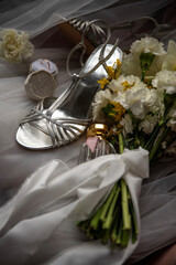 Silver bridal heels, wedding rings and floral bouquet close up