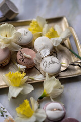 A tray holds macarons surrounded by fresh flowers and decorative items