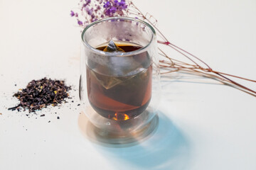 a clear glass cup filled with fragrant osmanthus oolong tea. The tea's amber color shimmers under...