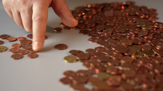 A man counts coins. A pile of coins on a gray table, which a man is counting.