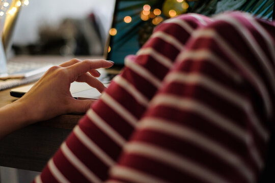 Close-up of a woman in leisurewear with her legs on the table using a laptop computer