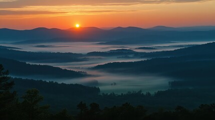 Obraz premium A sunrise view of a winding mountain road with mist in the valleys below.