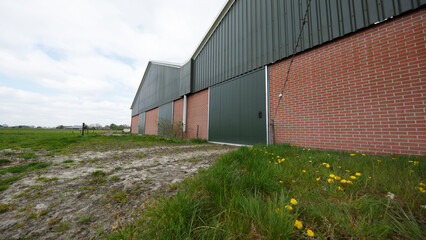 Farm building in Nederland showcasing typical architecture and natural surroundings amidst a cloudy sky