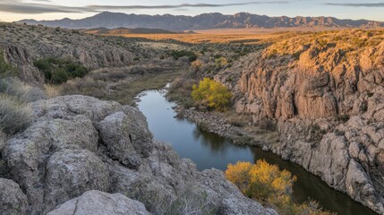 Sunrise casting a warm glow over a canyon surrounded by rugged mountains.