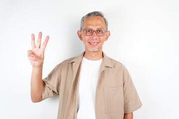Adult Asian Man showing three fingers sign, while smiling confident 
