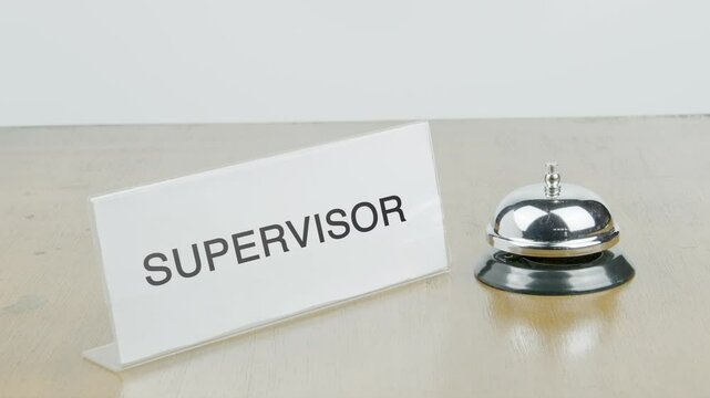 Supervisor Office or Room with Hand Ringing The Bell on Desk or Table Multiple Times