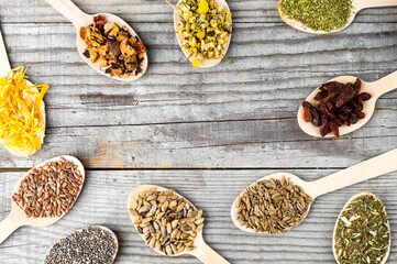 Herbal collection in wooden spoons: chamomile, calendula, dill and milk thistle seeds.Wooden Spoons with Dried Chamomile, Calendula, and Seeds on White Background. 