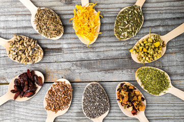 Herbal collection in wooden spoons: chamomile, calendula, dill and milk thistle seeds.Wooden Spoons with Dried Chamomile, Calendula, and Seeds on White Background. 