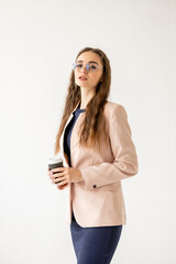 Portrait of an elegant woman in business clothes with a glass of coffee in her hands and wearing...
