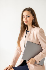 Portrait of an elegant woman in business clothes with a laptop in her hands sitting on an isolated white background.Vertical shot 
