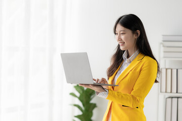 Young Asian woman digital nomad in office using laptop watching training video. Text message with...