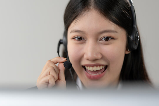 Smiling Asian woman wearing headset working in call center giving customer service consultation
