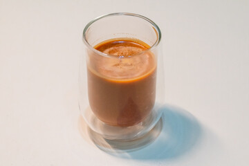 refreshing glass of Thai iced milk tea, served in a clear glass cup. The rich, vibrant orange color of the tea contrasts beautifully with the creamy milk at the bottom. A perfect blend