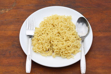 Top view of instant noodles spicy in white plate on wooden table background.