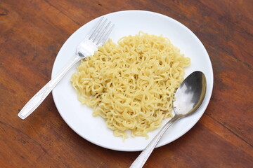 Top view of instant noodles spicy in white plate on wooden table background.