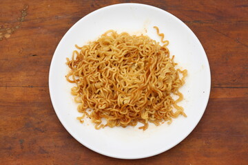 Top view of instant noodles spicy in white plate on wooden table background.
