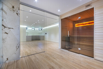 Spacious spa lounge with glass sliding doors. A modern sauna with bright lighting behind a .glass...