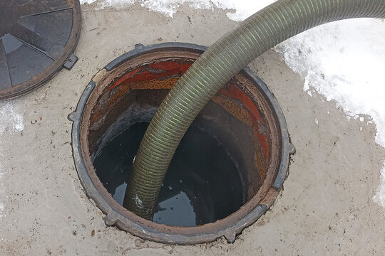 Pumping out a septic tank, a pipe in an overflowing cesspool close-up, cleaning the sewer system in a private home using a sewage truck