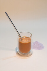 refreshing glass of Thai iced milk tea, served in a clear glass cup. The rich, vibrant orange color of the tea contrasts beautifully with the creamy milk at the bottom. A perfect blend