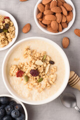 Oatmeal bowl with blueberries, granola, almonds and milk. Healthy breakfast concept.