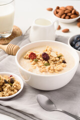 Oatmeal bowl with blueberries, granola, almonds and milk. Healthy breakfast concept.