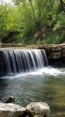 Fototapeta premium Serene waterfall surrounded by lush greenery and calm waters in a tranquil setting.